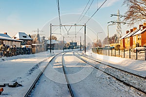 Front view of snow covered train tracks between houses and buildings