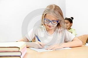 Front view of studious girl doing task on lesson in school