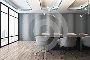 Front view on stylish dark conference table surrounded by chairs on wooden floor in empty spacious meeting room with grey slatted