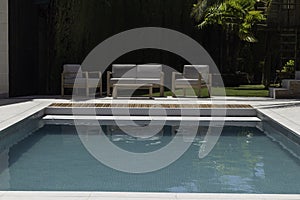 Front view of swimming pool with chill out sitting area and vegetation in the background with no people