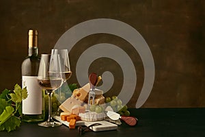 Front view of tasty cheese plate with the wine bottle on dark studio background