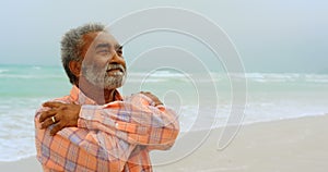 Front view of thoughtful active senior African American man shivering on the beach 4k