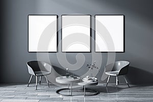 Front view on three blank white posters in black frame on dark wall background in grey shades living room with coffee table among