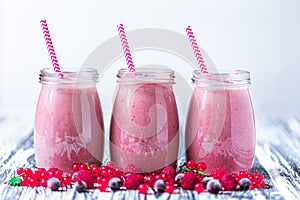 Front view of three jars with yogurt smoothie with cranberry, raspberry, blueberry on wood table
