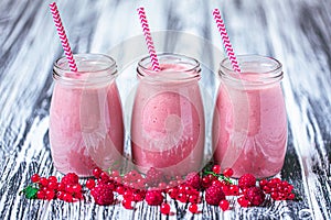 Front view of three jars with yogurt smoothie with cranberry, raspberry on wood table. Fruit dessert