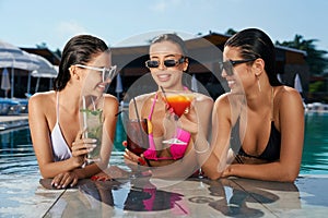 Three pretty girls standing in swimming pool.