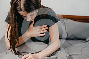 Front view of tired young woman feeling pain ache touching chest having heart attack. Sad worried girl suffers from heartache