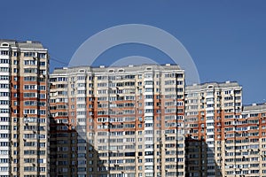 Front view to dense standing residential buildings under blue cloudless sky