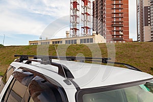 Front view of the top of a white metal crossover body on a roof on a summer day against a background of a residential building and