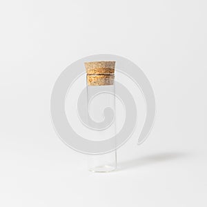 Front view of transparent empty glass jar or test tube bottle with closed brown cork cap lids on white background