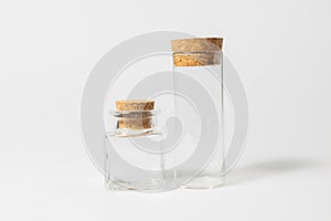 Front view of transparent empty glass jar or test tube bottles with closed brown cork cap lids on white background