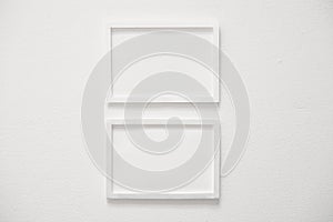 front view of two blank white horizontal photo frames hanging on clean white cement wall, interior design background concept