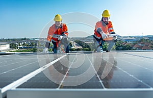 Front view of two Caucasian workers hold document pad and tablet check and maintenance the solar cell panels on rooftop of the