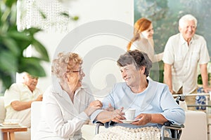 Front view of two happy geriatric women talking and holding hand
