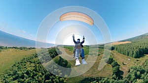 Front view of two people flying on the paraglider. Man Paragliding, beautiful nature background.