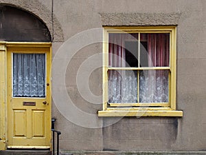 front view of a typical old small english terraced house with yellow painted door and window