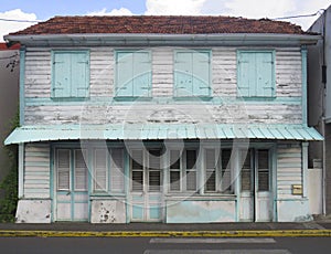 Front view of a typical wooden and rusted house in Martinique, French West Indies. Tropical blue and white windows photo