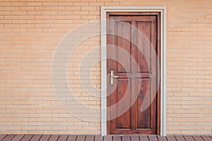 Front view vintage brown wooden door on red brick wall.