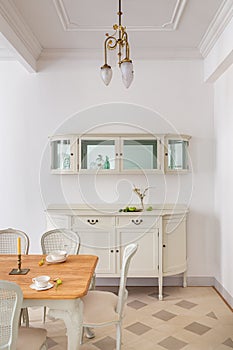 Front view of vintage style dining room with wooden table setting for two persons, tile floor and retro lamps