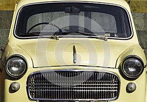 Front view of a vintage yellow car with a rounded body style and a horizontal chrome grill, circa 1950. photo