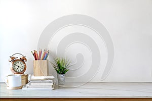 Front view of white desk with coffee mug and house plant. workspace and copy space