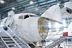 Front view of the white passenger airlines under maintenance in the aviation hangar