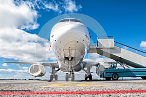 Front view of white passenger airplane with boarding ramp at the airport apron photo
