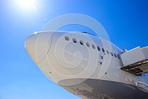 Front view of a white passenger plane waiting on the tarmac of an airport to receive passengers for flight