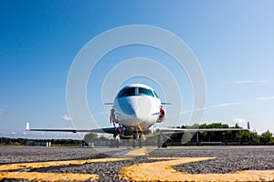 Front view of white private business jet at the parking lot of airport