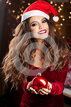 Front view of woman in red santa hat keeping christmas toy