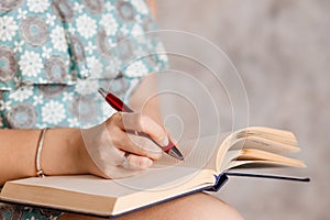 Front View of woman`s hands writing useful information in notepad.Girl`s hand with a red pen writes the task in notebook