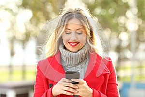 Front view of a woman using a smart phone in winter