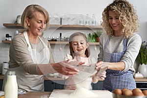 Front view of women sift the flour for Easter bake