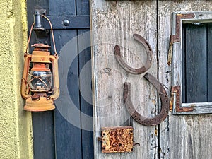 Front view of a wooden and metal door with a lamp and horseshoes