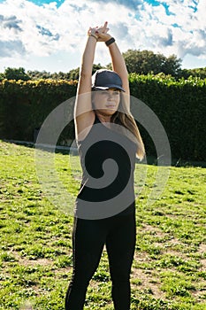 Front view of a young Caucasian woman in sportswear with arms outstretched in a park. Concept of outdoor pursuit in springtime and