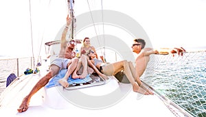 Front view of young millennial friends chilling on sailboat at sea ocean trip - Guys and girls having summer fun together at sail