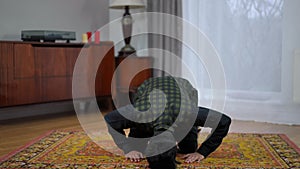 Front view young Muslim man bowing praying to Allah at home indoors. Wide shot portrait of handsome Middle Eastern male
