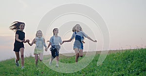 Front view of young pretty girls running together holding hand in hand, jumping, smiling, playing with hair. Kids