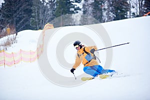 Proficient young skier concentrated on skiing down on steep ski slope. Extreme winter activities concept. Front view photo