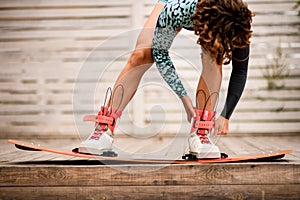 front view of young woman who fix her legs in boots on wakeboarding board