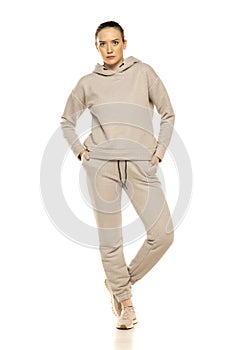 Front view of a young woman in a gray tracksuit posing to a white background in the studio