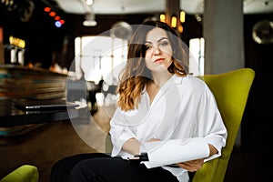 Front view. Young woman sits in cafe at a table, holding pen, reading documents. A businesswoman signs a contract. Startup,