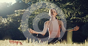 Front view of a young woman sitting on yoga mat in lotus position and deeply breathing. Beautiful girl practicing yoga