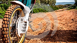 Front wheel of an adventure bike on a dirt road with mud