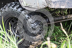 The front wheel of an off-road car on the grass after driving through mud