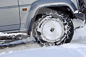 Front wheel of vehicle driving on snow winter road