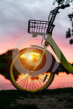 Front wheel of a yellow bike on the lake. Sunset