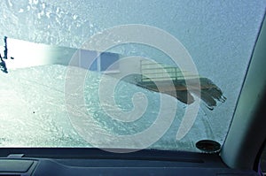 The front windshield of a car is scraped from the ice in winter, inside view