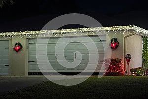 Front yard with brightly illuminated christmas decorations on driveway to house garage. Outside decor of florida family