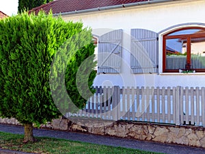 front yard with classic white picket fence along sidewalk. vertical painted wood planks. green garden